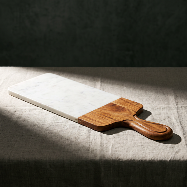 Marble and mango wood serving board with carved handle on table