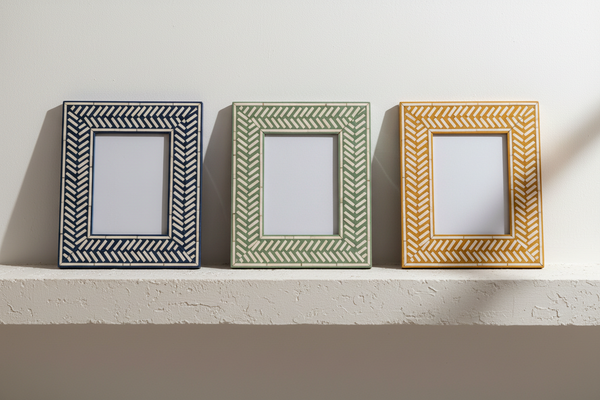 Three bone inlay photo frames in indigo, verdigris and ochre herringbone, side by side on a pale shelf